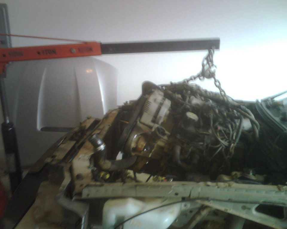 Engine being removed from a car with an engine hoist