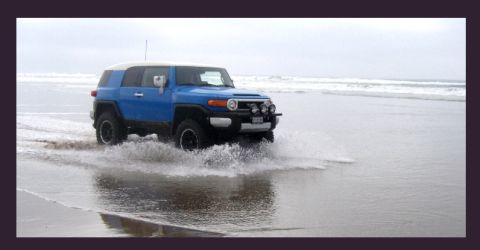2007 Toyota FJ Cruiser - Blue 2007 Toyota FJ Cruiser driving through shallow water on a beach with waves in the background.
