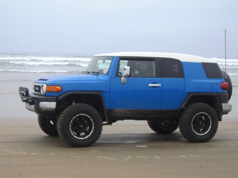 2007 Toyota FJ Cruiser - This blue 2007 Toyota FJ Cruiser is parked on the sand with waves in the background.