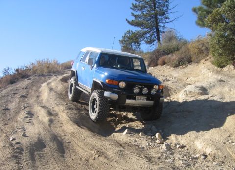 2007 Toyota FJ Cruiser - A blue 2007 Toyota FJ Cruiser navigates a challenging off-road course on a sunny day.