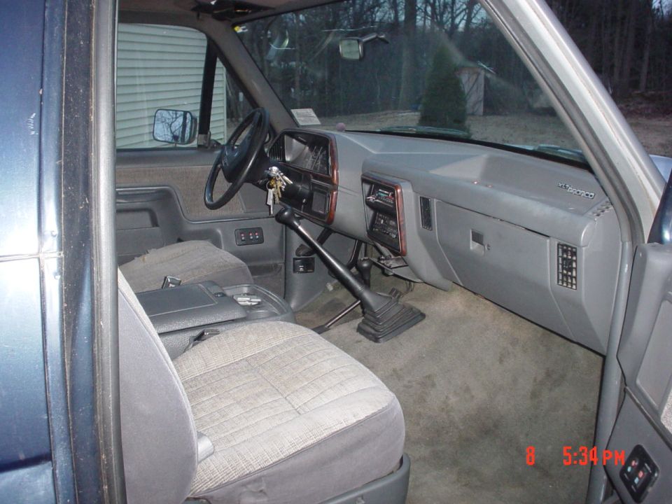 Interior of a 1990 Ford Bronco showing the dashboard, steering wheel, and seats