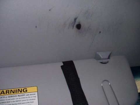 1998 Ford Crown Victoria - Close-up of a vehicle's interior ceiling, showing some marks and a sun visor with a warning label.