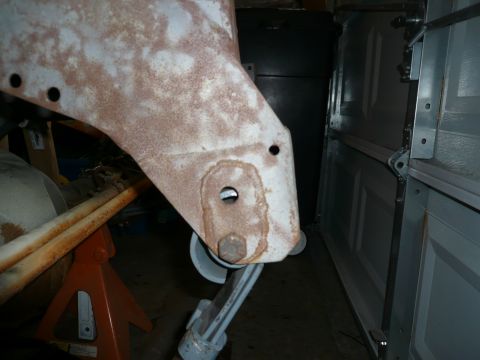 1974 Land Rover Land Rover - A close-up view of a heavily rusted vehicle frame component supported by jack stands in a garage setting.