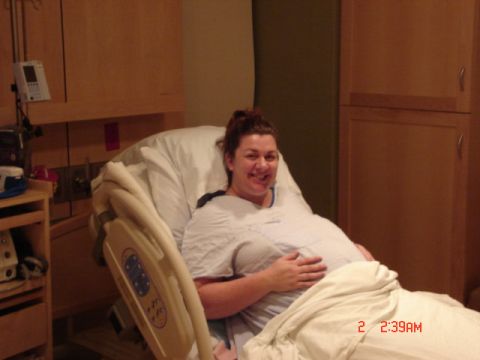 1981 Ford Bronco - A woman smiles while holding her pregnant belly in a hospital bed.