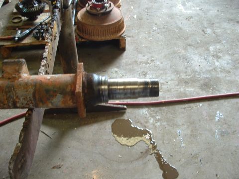 1979 Ford Bronco - A rusty axle spindle is shown with a metal shaft, likely part of a vehicle repair or modification project.