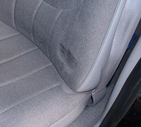 1998 Ford Crown Victoria - Close-up view of a gray fabric car seat interior, showing the texture and a noticeable stain on the cushion.