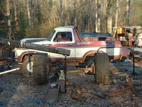 1979 Ford Bronco - This two-tone red and white Ford Bronco appears to be undergoing modifications with large tires and a crane boom attached.