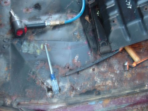 1979 Ford Bronco - This photo shows extensive rust damage on the vehicle's floor pan, with tools present.