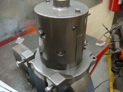 1996 Ford Bronco - A gray painted winch motor is secured in a vise, ready for work or inspection.