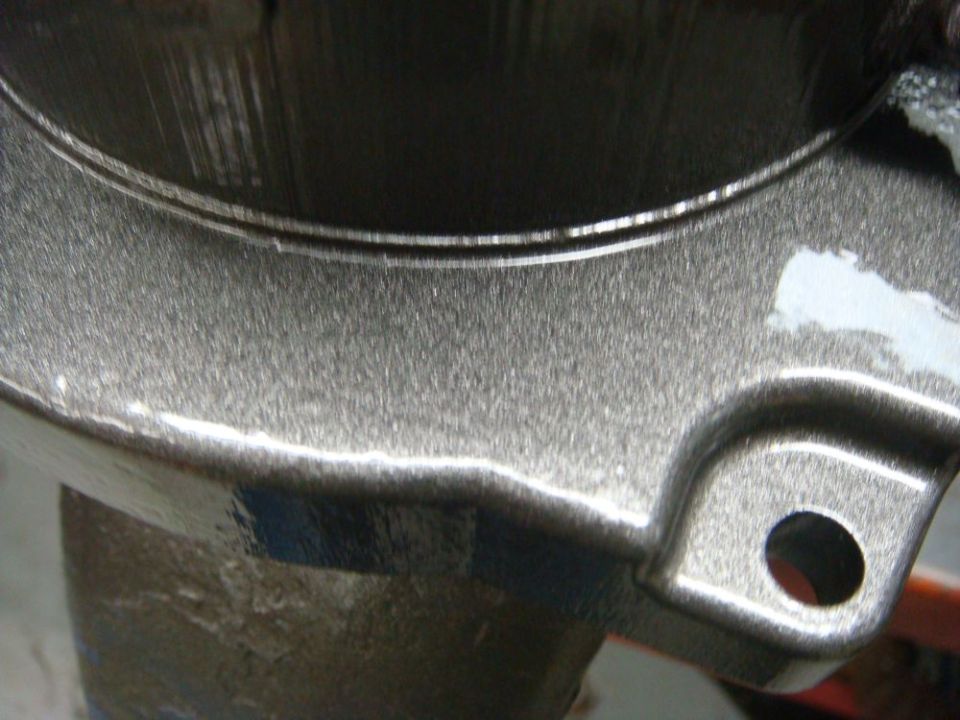 Close-up of a metallic gray painted part with a textured finish and a mounting hole