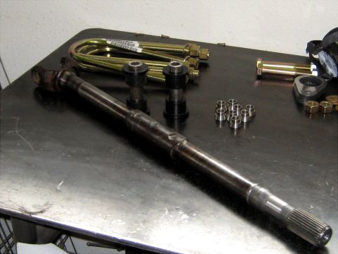 1996 Ford Bronco - Various automotive parts, including a driveshaft and suspension components, laid out on a workbench.