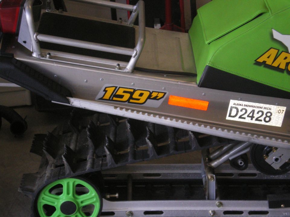 Green Arctic Cat snowmobile side showing 159 decal, reflector, Alaska decal D2428, and track.