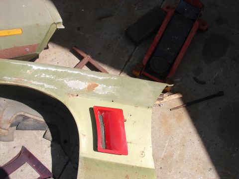1973 Ford Ranchero - A pale green front fender lies face-up on a concrete floor with a red rectangular side marker lamp housing fitted into the panel and body f…