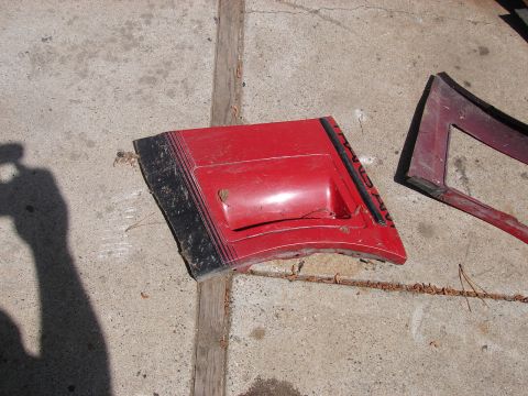 1973 Ford Ranchero - Red sheetmetal hood scoop panel with black striping and raised lettering laid on a concrete driveway, its underside dirty and paint chipped…