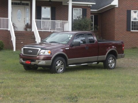 2005 Ford F-150 - Maroon 2005 Ford F-150 pickup truck with tan trim parked in front of a residential home.