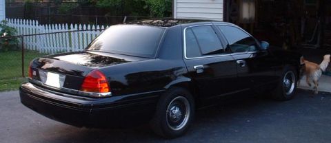1998 Ford Crown Victoria - A black 1998 Ford Crown Victoria is parked in a driveway next to a white picket fence.