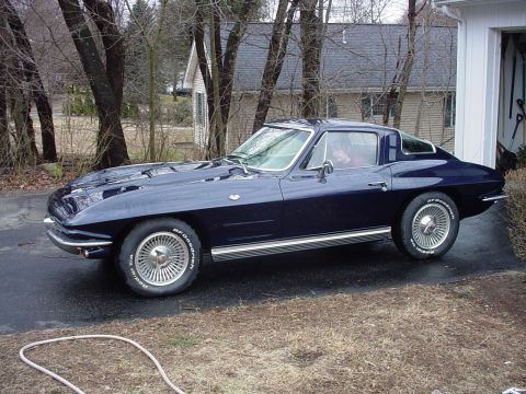 1964 Chevrolet Corvette - A dark blue coupe is parked in a driveway next to a garage.