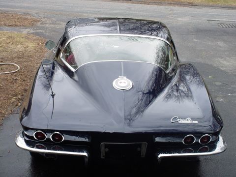 1964 Chevrolet Corvette - Rear view of a dark blue Chevrolet Corvette, showing its iconic quad taillights and chrome accents.