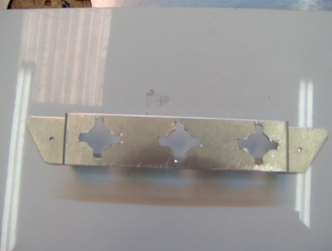 1978 Ford Bronco - A metal bracket with decorative cutouts is shown against a light background.