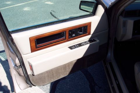 2001 Ford Crown Victoria - Close-up of a car's interior door panel, wood trim and various power controls.