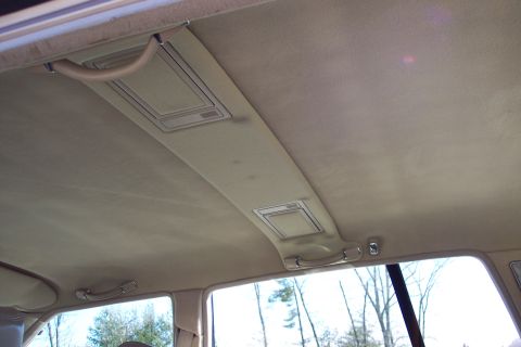 2001 Ford Crown Victoria - The interior ceiling of a car shows two overhead lights and tan grab handles.
