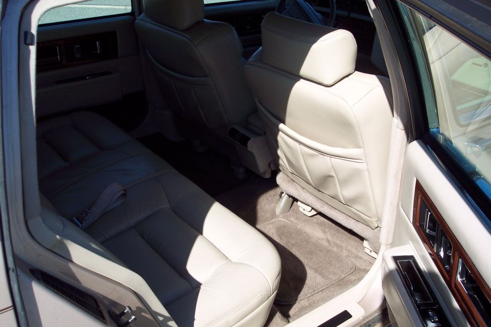 Interior rear seats of a car with beige leather upholstery and wood trim