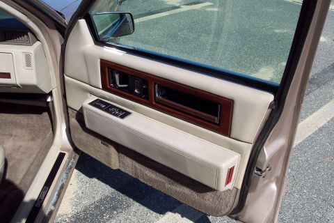 2001 Ford Crown Victoria - The interior door panel of a 1993 Cadillac Sixty Special shows wood trim and beige leather upholstery.