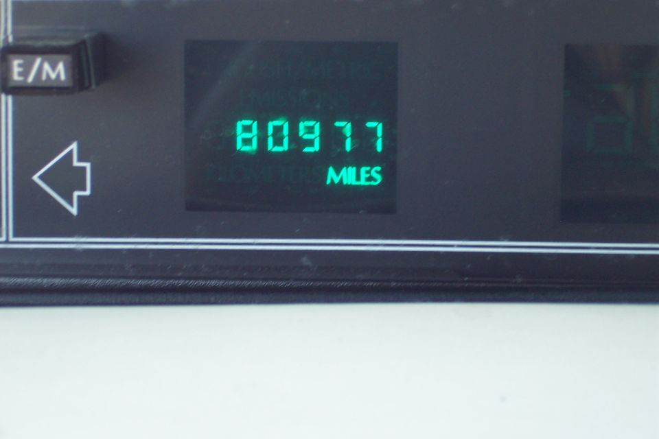 Digital odometer shows 80977 miles. E/M button and left turn signal indicator visible
