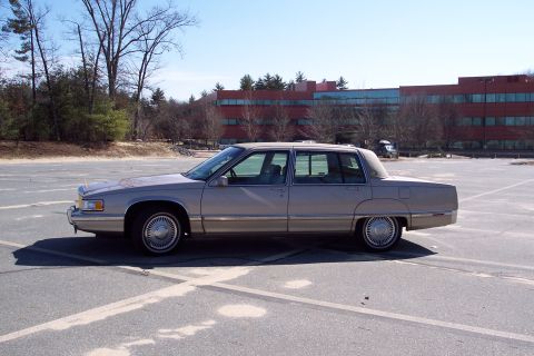 2001 Ford Crown Victoria - This tan Cadillac sedan is viewed from the side in a parking lot.