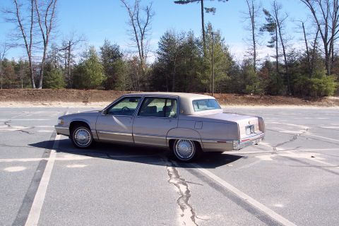 2001 Ford Crown Victoria - This tan sedan is seen from the rear quarter angle in an empty parking lot.