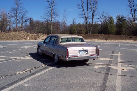 2001 Ford Crown Victoria - Rear view of a 1993 Cadillac sedan parked in an outdoor lot under a clear blue sky.