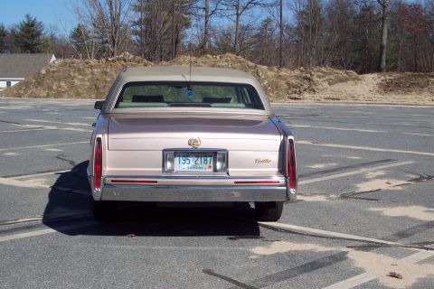 2001 Ford Crown Victoria - This Cadillac sedan has a tan vinyl roof and a chrome bumper. The license plate is from New Hampshire.