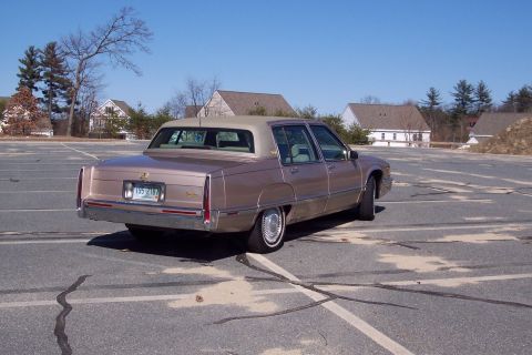 2001 Ford Crown Victoria - This Cadillac sedan is parked in an empty lot under a clear blue sky.