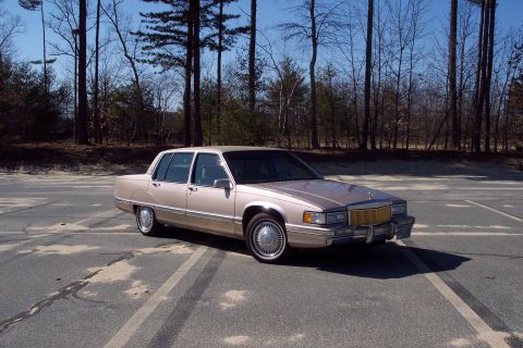 2001 Ford Crown Victoria - This Cadillac sedan is parked in an outdoor lot with bare trees visible.