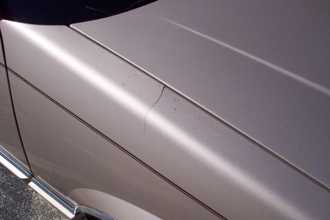 2001 Ford Crown Victoria - Close-up view of a car's fender and hood shows a crack and a pinstripe detail.