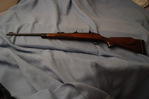 1991 Ford Bronco - A rifle with a wooden stock and a dark barrel is displayed on a soft blue fabric surface.