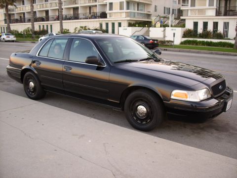 2005 Ford Crown Victoria - A black 2005 Ford Crown Victoria is parked curbside in front of apartment buildings.