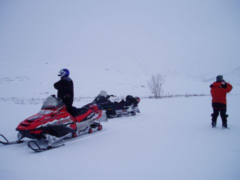 2000 Ford E350 - Two snowmobiles are parked in a snow-covered field with two individuals present.