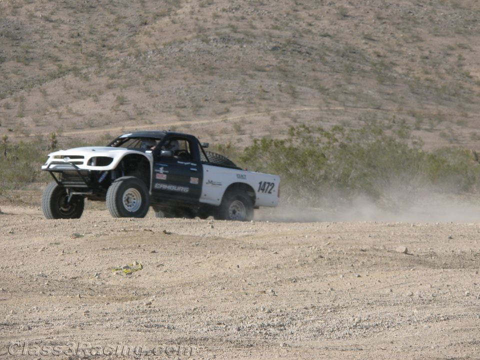 White off-road race truck no. 1472 cornering on a desert course