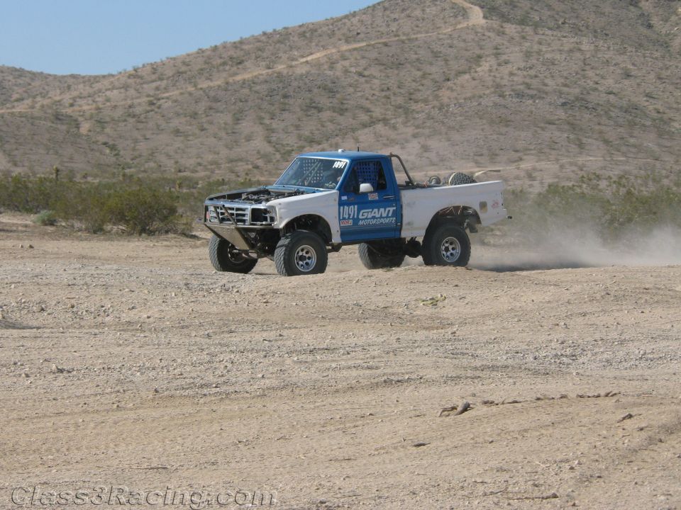 White off-road race truck no. 1491 with Giant Motorsports livery on a desert course