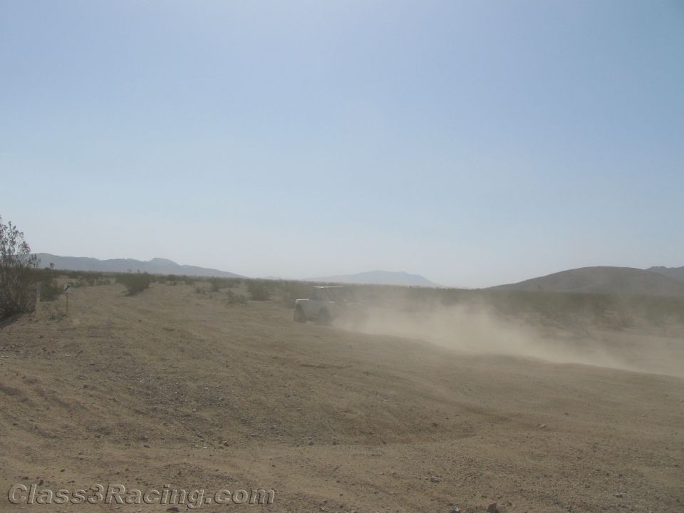 Off-road vehicle nearly hidden in a thick dust cloud on a desert course