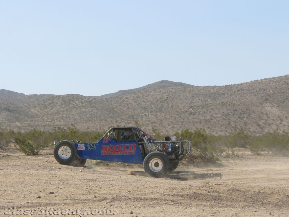 Blue and red off-road race buggy kicking up dust in the desert