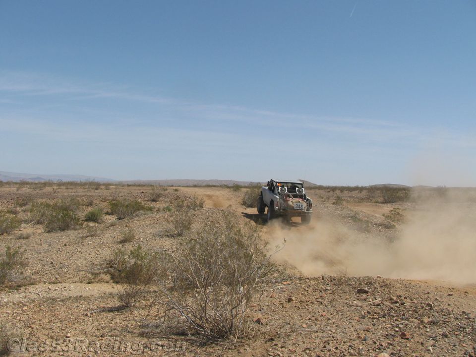 Off-road buggy racing head-on across brushy desert terrain