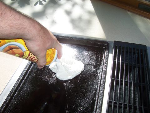 1994 Ford F-150 - A hand dispenses pancake batter from a can onto a hot griddle, with a grill grate visible to the side.