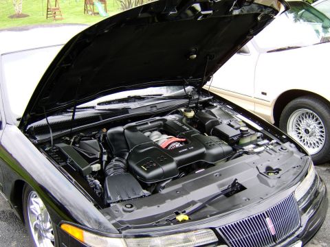 1996 Mercury Grand Marquis - The engine bay of a black car is shown with the hood open, parked next to a cream-colored vehicle.