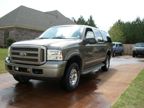1995 Ford Bronco - A gray Ford Excursion is parked in a driveway with two other trucks visible in the background.