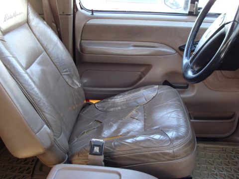 1992 Ford Bronco - The interior of a 1992 Ford Bronco shows a worn leather driver's seat and part of the dashboard.