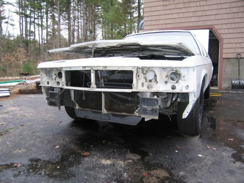 1991 Ford LTD Crown Victoria - The front end of a white sedan is disassembled, with the hood open and missing its grille and headlights.