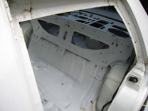 1991 Ford LTD Crown Victoria - Car interior stripped down to bare metal, showing the rear seat area and floor pan.