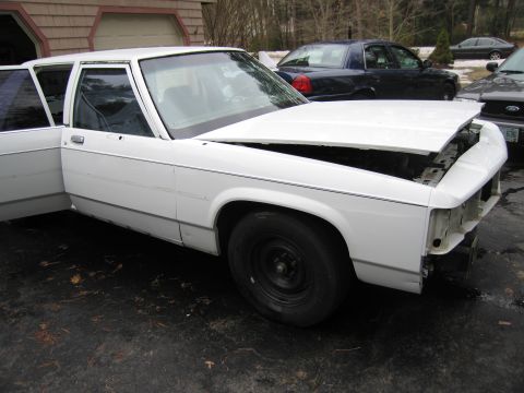 1991 Ford LTD Crown Victoria - This white sedan appears to be a Ford Crown Victoria, but the model year is not definitively 1991 based on its styling.